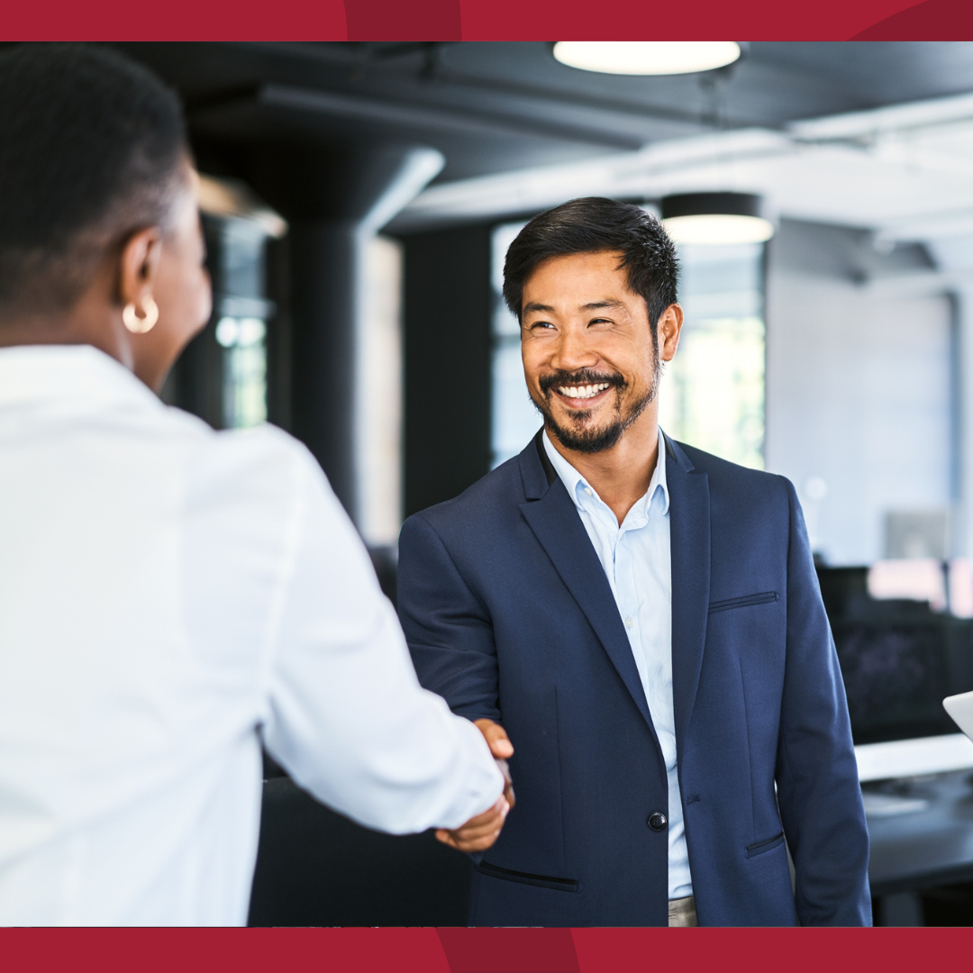 A man and a woman are shaking hands in an office setting.